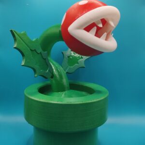 Figurine de Plante Piranha inspirée de Mario, avec tête rouge et blanche et tuyau vert, vue de trois quarts.