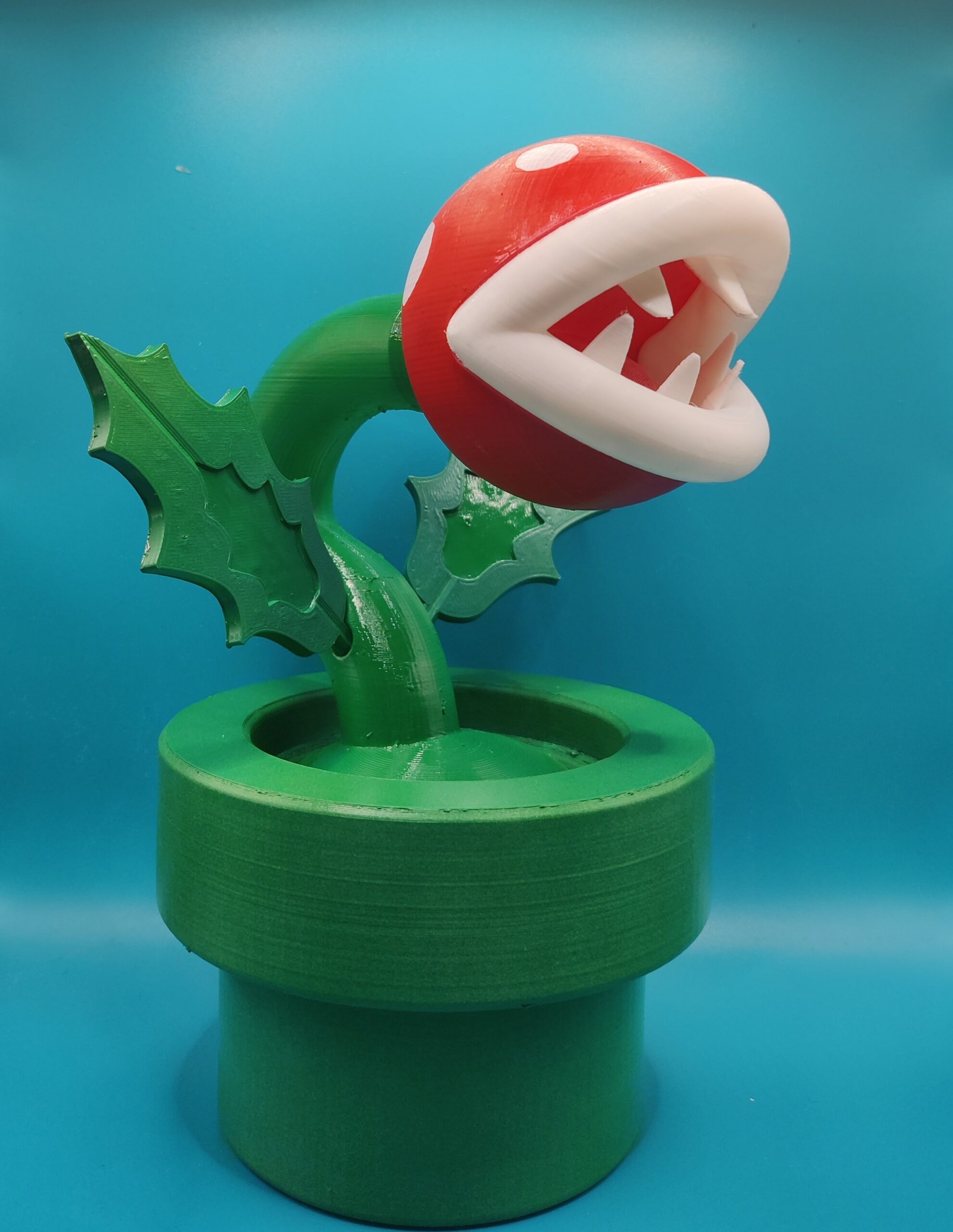 Figurine de Plante Piranha inspirée de Mario, avec tête rouge et blanche et tuyau vert, vue de trois quarts.