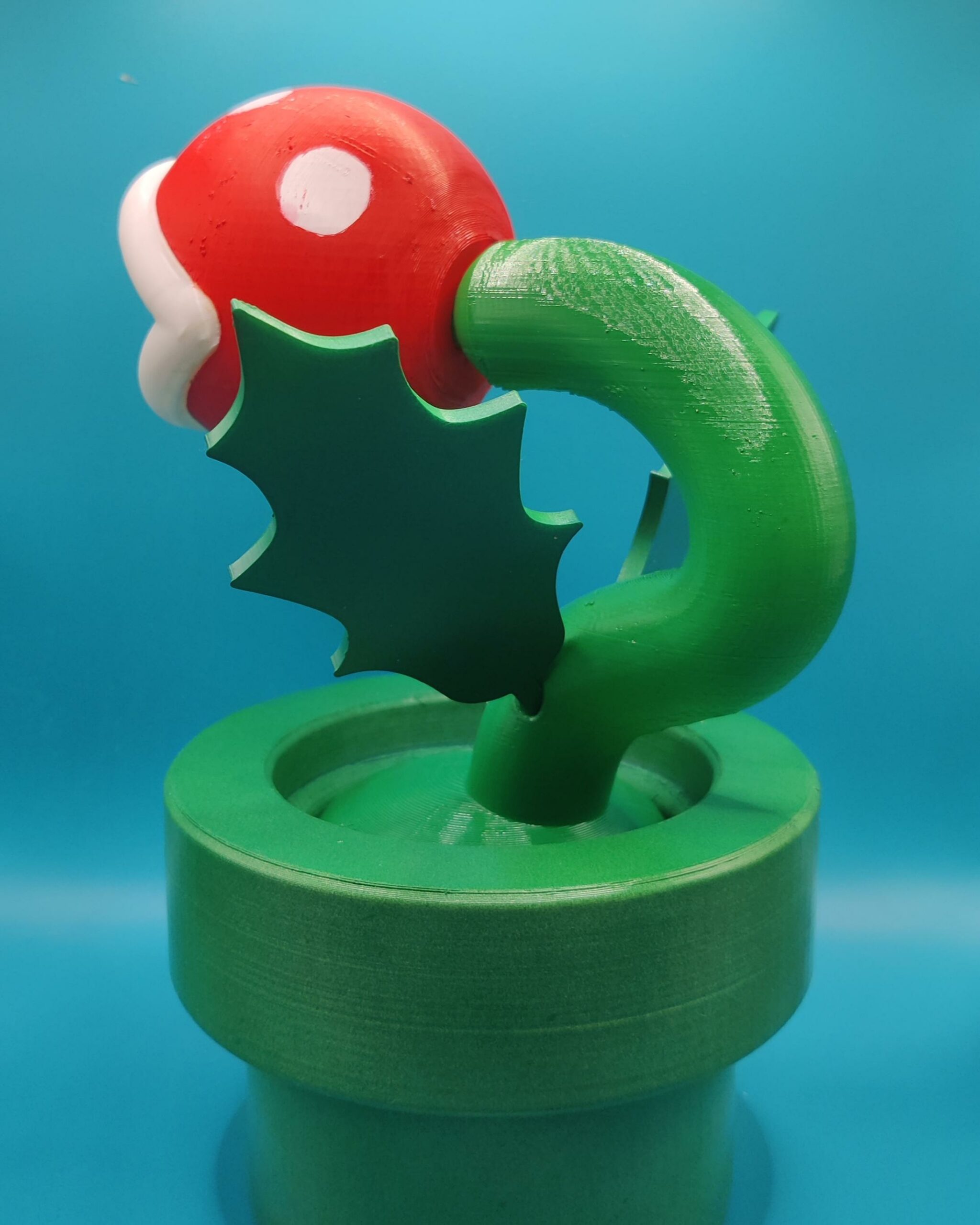 Plante Piranha Mario – Vue arrière ‣ Atelier 34 Vue arrière de la figurine de Plante Piranha, montrant la tige courbée et les feuilles sur le tuyau vert.