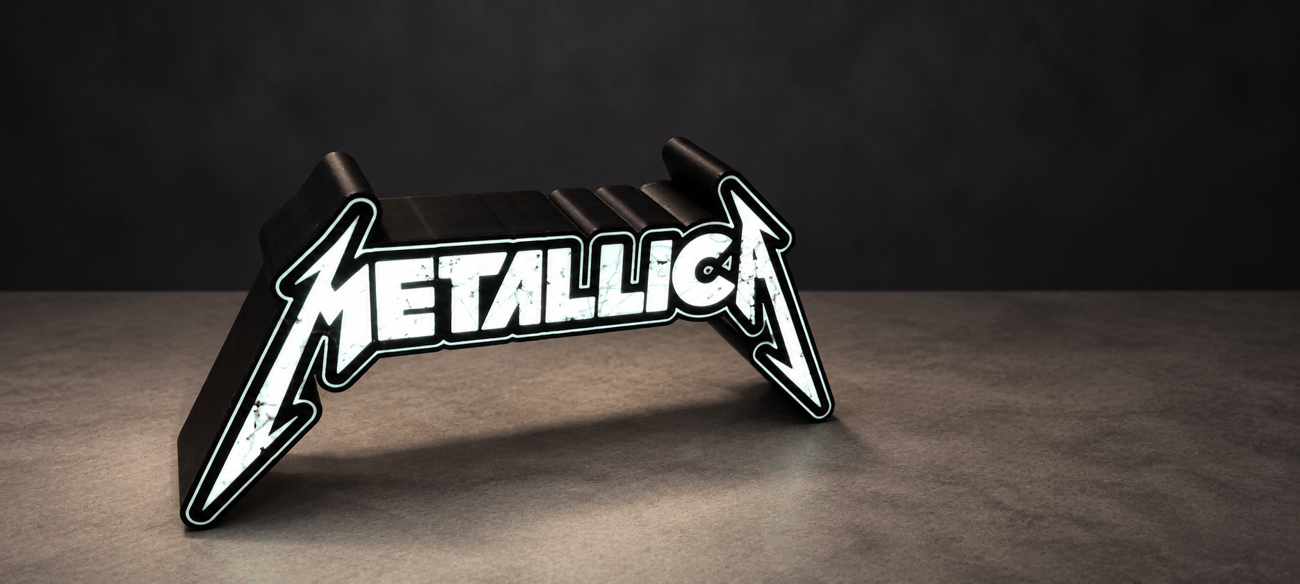 Lightbox Metallica – photo principale ‣ Atelier 34 Lightbox Metallica allumée sur fond sombre, vue de face et de trois quarts