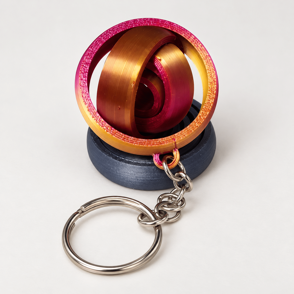 Porte-clé gyroscope silk bicolore - ouvert ‣ Atelier 34 Porte-clé gyroscope articulé en filament silk bicolore, anneaux ouverts.