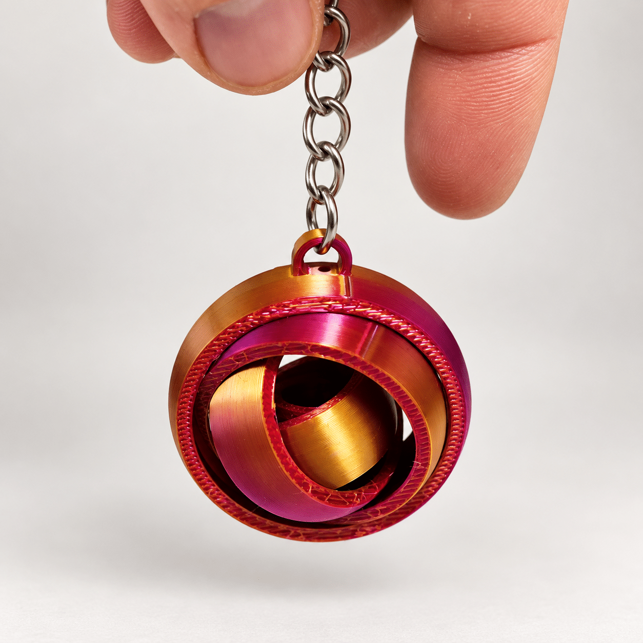 Porte-clé gyroscope silk bicolore - suspendu ‣ Atelier 34 Porte-clé gyroscope articulé en filament silk bicolore, suspendu.